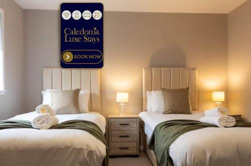 two beds in a hotel room with towels at Grove House in Queensferry