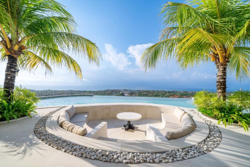 an outdoor patio with a table and two palm trees at Casa Daria Sofia - Ocean Views Infinity Pool Escape with Cinema & Gym in Uluwatu