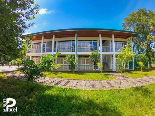 um grande edifício branco com árvores na frente em Tabbowa Lake Resort em Nikawatawana