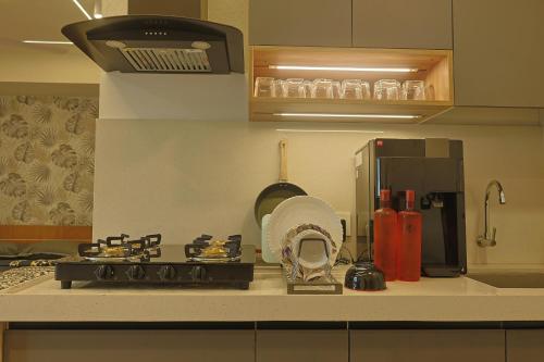a kitchen counter with a stove and a refrigerator at Studio at walking distance from airport in Pune