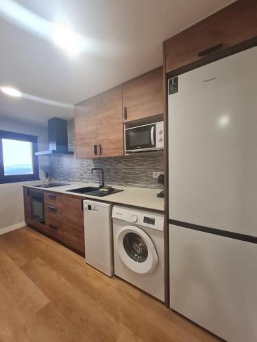 a kitchen with a washing machine and a refrigerator at Casa Mauricio in Gúdar