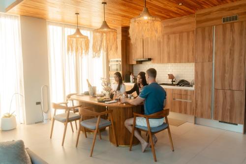 a group of people sitting at a table in a kitchen at Pai Prestige - Luxury Pool Villas in the centre of Pai in Pai