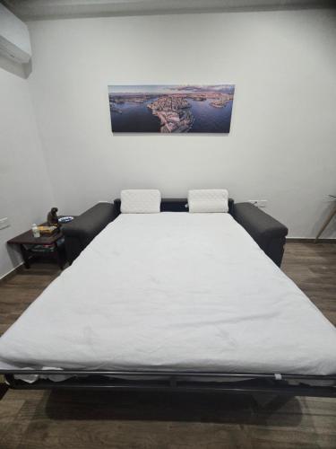1 cama blanca grande en una habitación con una pintura en la pared en Studio Groundfloor Apartment, en Il-Gżira