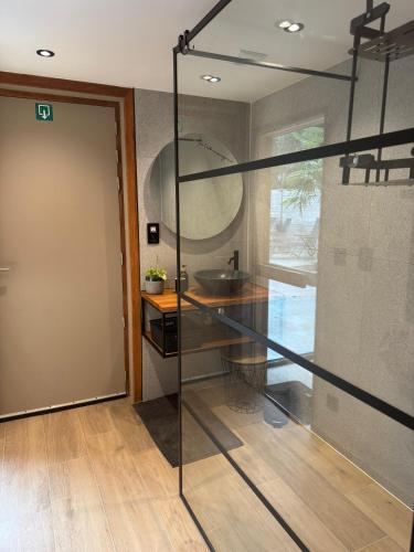 a bathroom with a glass door and a sink at B&B Wellness Garden in Herzele