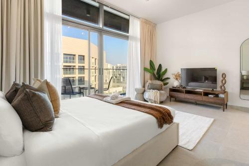 a white bedroom with a large bed and a television at Silkhaus Vacation Homes Holiday Studio Retreat in Saadiyat Island in Abu Dhabi