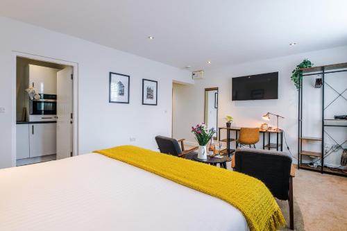 a bedroom with a large white bed with a yellow blanket on it at Riverside Studios in the Centre of Chester in Chester