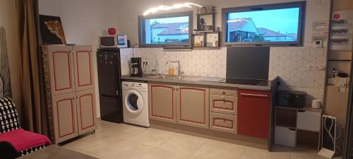 Confort & Calme في سانت جيل كروا دي فيي: مطبخ مع دواليب برتقال وغسالة ملابس