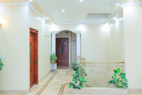 a hallway with white walls and a door with plants at Majestic BnB in Karachi