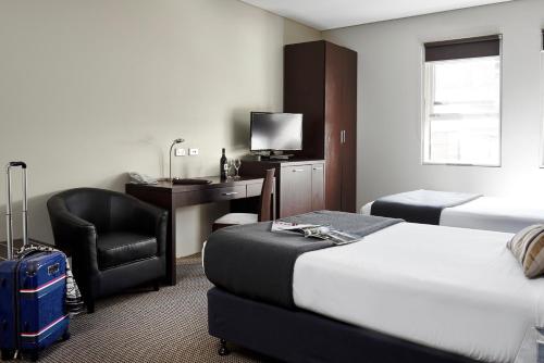 una camera d'albergo con letto, scrivania e sedia di Vulcan Hotel Sydney a Sydney