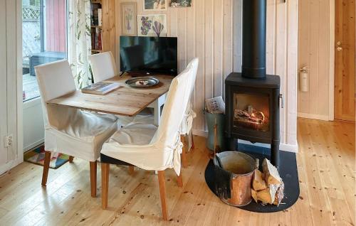 1 Bedroom Stunning Home In Blidö في Lagervik: غرفة طعام مع طاولة وموقد خشبي