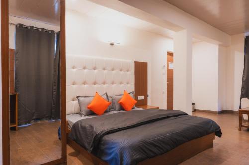 a bedroom with a large bed with orange pillows at Hotel Morainic Hills Mall Road Bhagsunag in McLeod Ganj