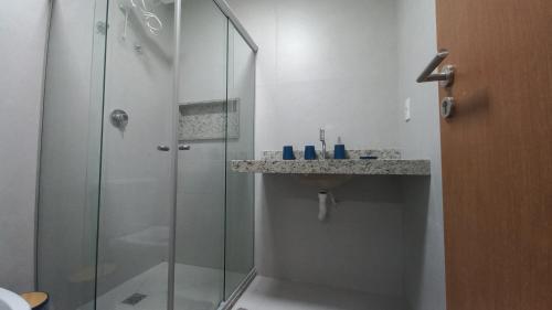 a bathroom with a glass shower and a sink at Apto Pe na Areia com Piscina Privativa in Ipioca