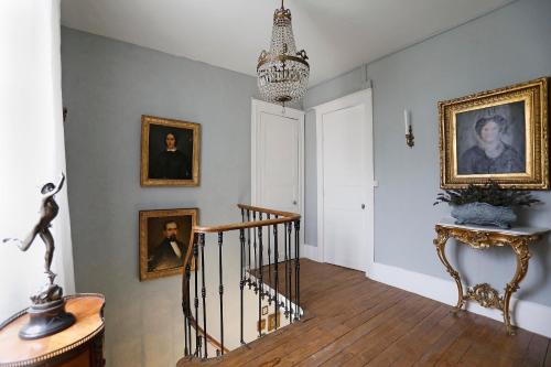 a hallway with a staircase with portraits on the wall and a chandelier at Villa La Poste 