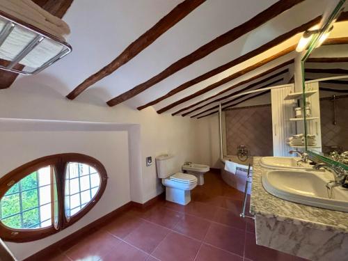 Un baño con lavabo, inodoro y espejo. en Hotel Casa de los Arcos, en Vélez Blanco