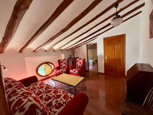 Una sala de estar con sillas rojas y una mesa. en Hotel Casa de los Arcos, en Vélez Blanco