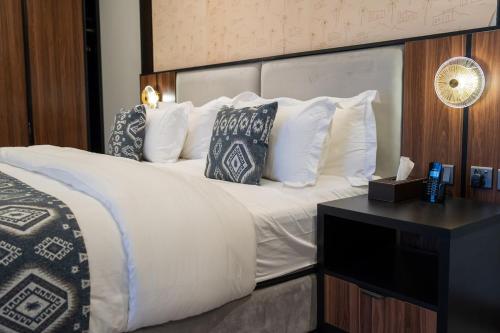 a bedroom with a large white bed with pillows at Jovan Suites apartment 2 in AlUla