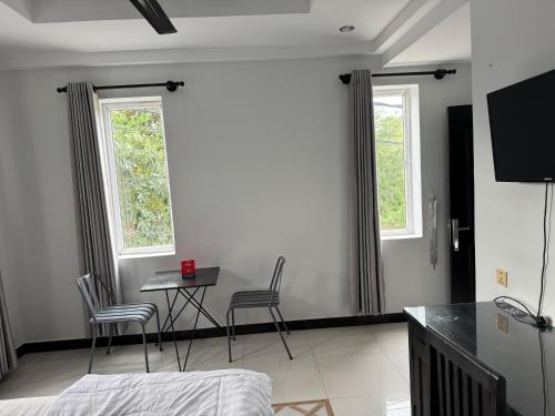 a bedroom with a table and chairs and two windows at Villa de Sancho in Phumĭ Réach Born