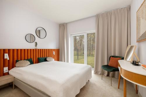 a bedroom with a bed and a desk and a window at Apartamenty Joy Me Łukęcin in Łukęcin