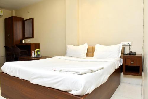 a bedroom with a large bed with white sheets at Raj Gharana in Raipur