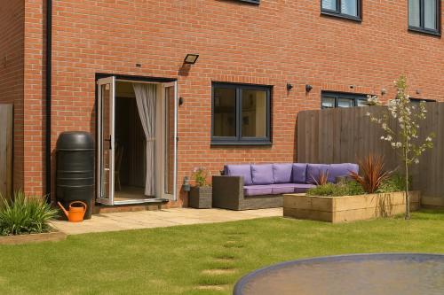 a purple couch in a yard next to a brick building at The Nest Retreat Exeter in Exeter