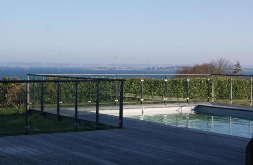 een houten terras met een zwembad en een hek bij Villa Residence Kersaliou in Roscoff