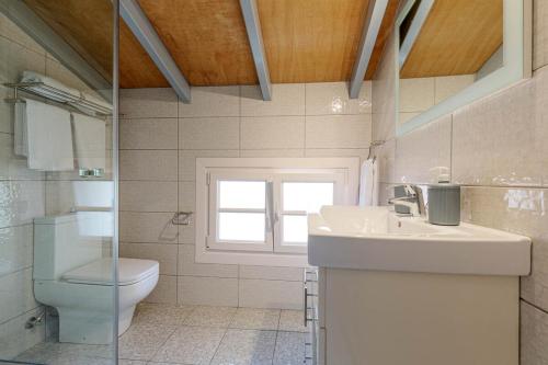 a bathroom with a toilet and a sink and a window at Sunny Skylight Loft! in Ágios Rókkos