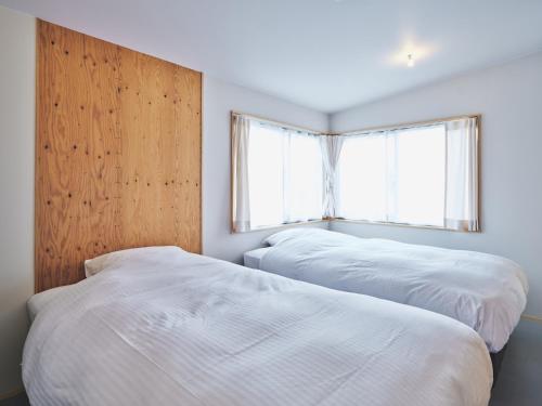 zwei Betten in einem Schlafzimmer mit Fenster in der Unterkunft TABiE in Izumo