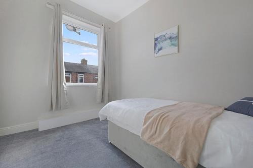 een witte slaapkamer met een bed en een raam bij Frances Terrace Haven in Bishop Auckland