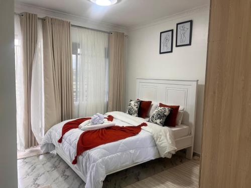 a bedroom with a large bed with red and white sheets at Studio in Nanyuki with Mount Kenya Views in Nanyuki