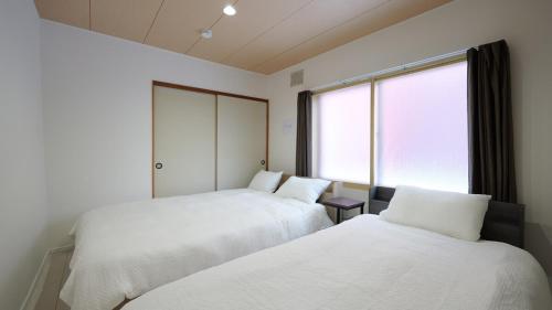 a bedroom with two beds and a large window at Toko92 in Asahikawa