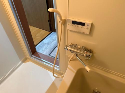 a bathroom with a hose attached to a wall at Toko92 in Asahikawa