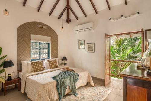 een slaapkamer met een bed en een balkon bij Sanctuary by RÊVE Escapes - Premium 3 BHK Villa with Private Pool Near Morjim Beach in Siolim
