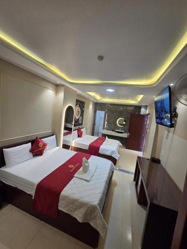 a hotel room with two beds and a television at Khách Sạn Hoa Vinh - Thủ Đức in Ho Chi Minh City
