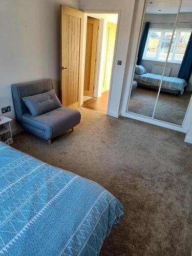 a bedroom with a bed and a chair and a mirror at Countryside 2 Bed Bungalow with Stunning Views Free WiFi and Parking Ideal for Business and Leisure in Great Addington