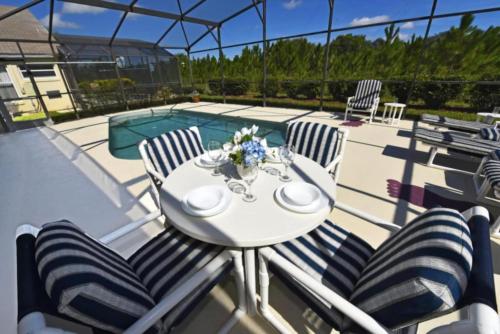 a white table and chairs on a patio with a pool at Rise & Shine! in Orlando