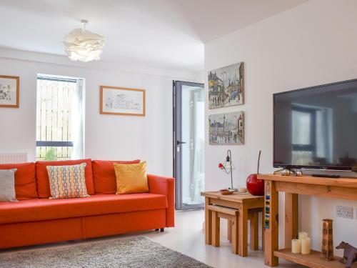 a living room with a red couch and a flat screen tv at Potters Pad in Alnwick