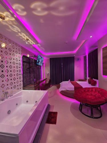 a bedroom with a tub and a bed with purple lighting at Khách Sạn Hoa Vinh - Thủ Đức in Ho Chi Minh City