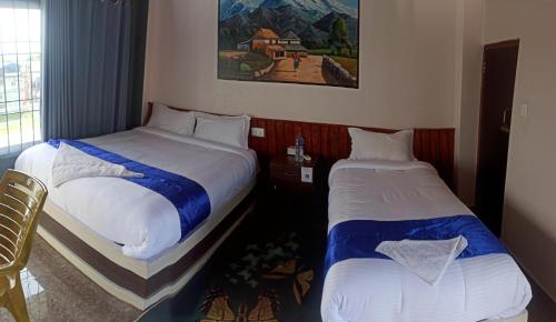 a hotel room with two beds and a picture on the wall at Hotel namo buddha in Sauraha