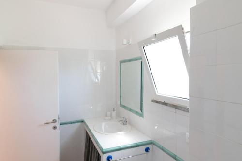 a white bathroom with a sink and a mirror at Verde Blu Scirocco Lake Front Apartment Trevignano Romano in Rome