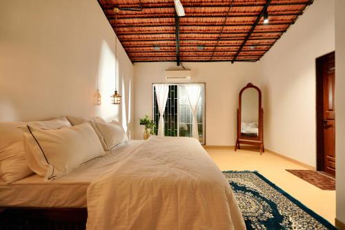 a bedroom with a large bed with a wooden ceiling at NOSSA GOA VILLA in MUMBAI GORAI in Mumbai