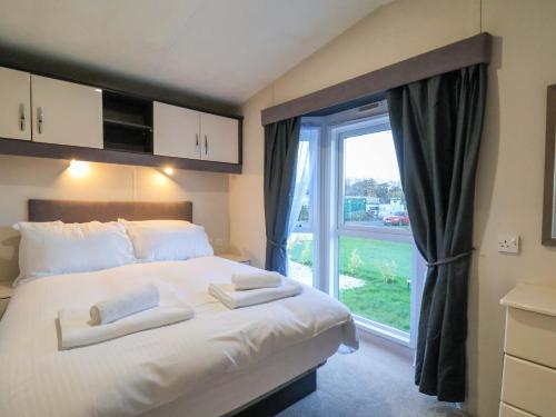 een slaapkamer met een groot bed en een groot raam bij Rosefinch Cabin in Staintondale