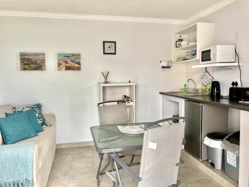 Southern Blue Agulhas في أقولاس: مطبخ وغرفة معيشة مع طاولة وأريكة