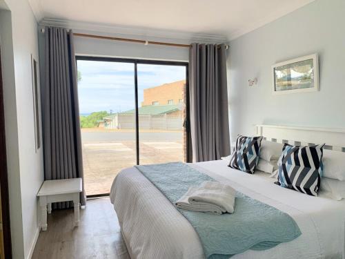 Southern Blue Agulhas في أقولاس: غرفة نوم بها سرير ونافذة كبيرة