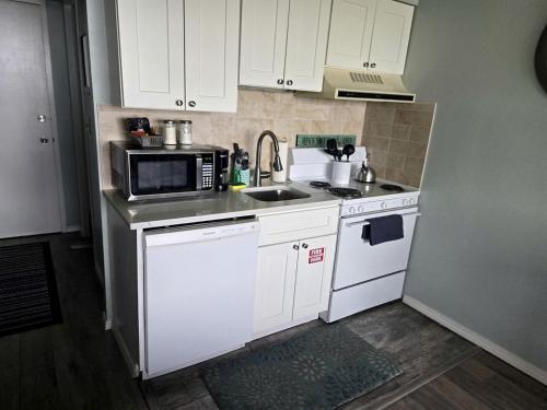 a small kitchen with white cabinets and a microwave at Relaxing Lakeside Getaway with Stunning Lake Views Near Gunstock | Laconia, NH in Weirs Beach