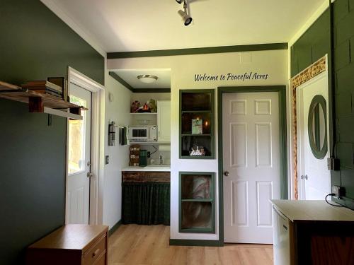 Cute Cozy Suite Rental Nestled on Beautiful Private Grounds for a Peaceful Getaway near Columbus, Ohio في Gould Park: مطبخ بجدران خضراء وباب ابيض