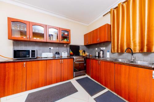 a kitchen with wooden cabinets and a sink at Luxury Homes and Apartments - Near Entebbe Airport in Kampala