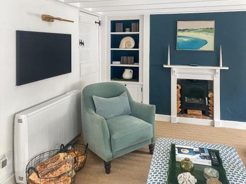 a living room with a green chair and a tv at Shearwaters in Saint Mawes