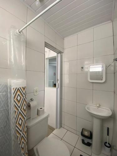 a white bathroom with a toilet and a sink at Ao lado do Hospital Calixto apartamento térreo in Itabuna
