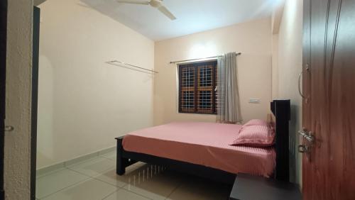 a bedroom with a bed with pink sheets and a window at Gokula Arcade in Subrahmanya