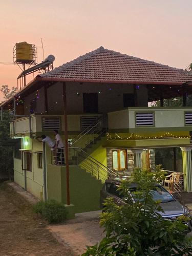 ein Mann steht auf dem Balkon eines Hauses in der Unterkunft Vanashree Homestay Galamudi in Sringeri
